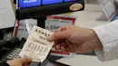 Seorang pelanggan menyerahkan tiket lotre Powerball di Omaha, AS (23/8). (AP Photo/Nati Harnik)