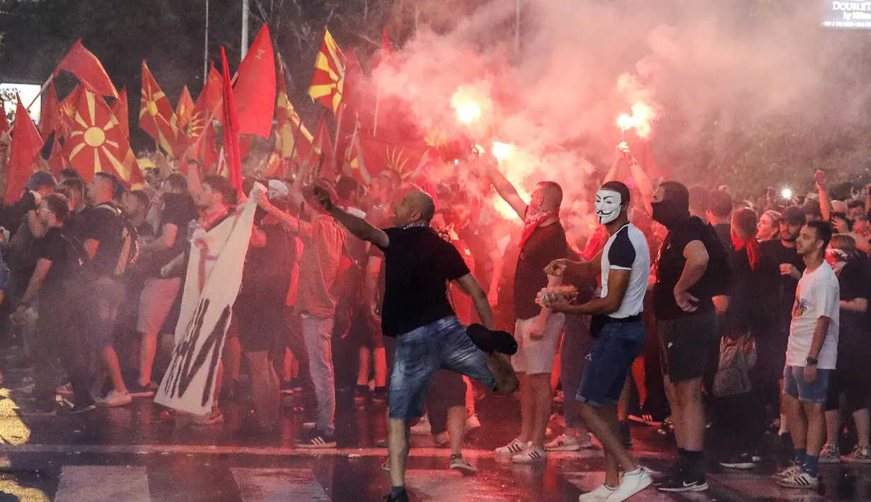 Orang-orang menyalakan suar dan melemparkan telur dan batu ke gedung kementerian luar negeri selama protes di Skopje, Makedonia Utara, Selasa (5/7/2022) malam. Protes kekerasan meletus di ibu kota Makedonia Utara, Skopje, di mana para demonstran mencoba menyerbu gedung-gedung pemerintah. (AP Photo/Boris Gdanoski)