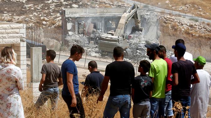 Warga Palestina menyaksikan pasukan Israel menghancurkan bangunan palestina di Yerusalem (22/7/2019).Penghancuran terkait putusan pengadilan tinggi Israel pada Juni 2019 lalu yang menolak petisi warga Palestina yang meminta pembatalan perintah militer melarang konstruksi. (AFP Photo/Ahmad Gharabli)