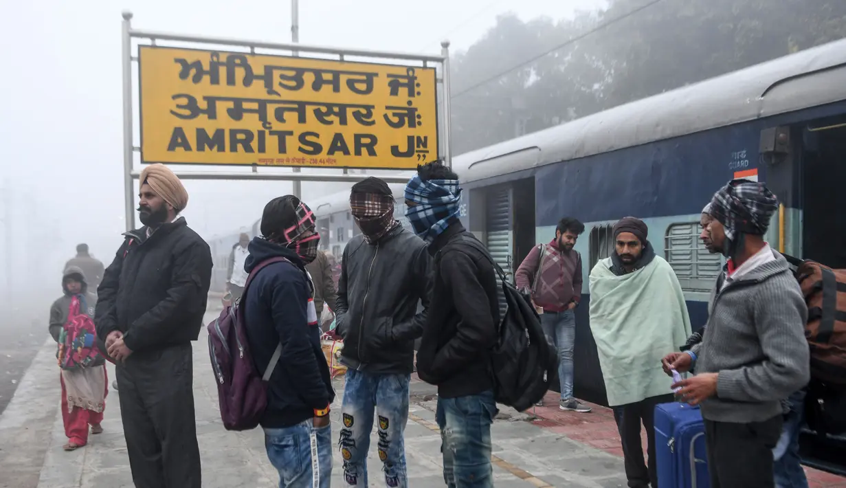 Penumpang menunggu kereta api di tengah kabut tebal selama hari yang dingin di stasiun kereta api di Amritsar, India (30/12/2019). (AFP/Narinder Nanu)