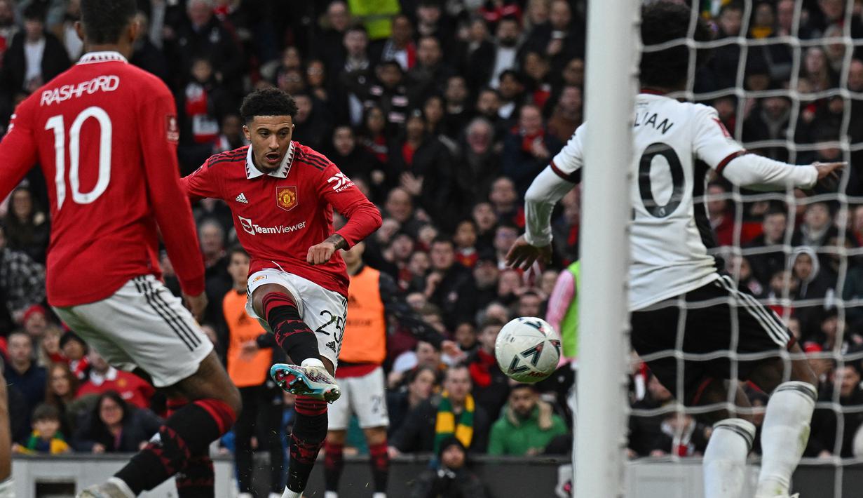 Gelandang Manchester United, Jadon Sancho melepaskan tendangan yang masih membentur gelandang Fulham, Willian pada laga perempatfinal Piala FA 2022/2023 di Old Trafford Stadium, Manchester (19/3/2023). Sempat diincar lama, Jadon Sancho akhirya berlabuh di MU dari Borussia Dortmund pada awal musim 2021/2022 dengan nilai transfer 85 juta euro. Dua musim bersama MU, penampilannya masih jauh dari ekspektasi. MU pun siap melepasnya pada bursa transfer musim panas 2023. (AFP/Paul Ellis)