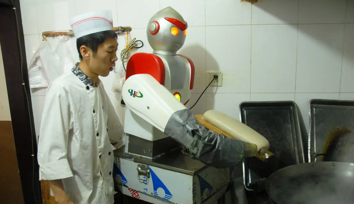 Seorang koki melihat robot yang sedang membuat mie di sebuah restoran,  Beijing , Cina , 14 April 2016. Kita akan melihat berbagai kebiasaan unik warga Cina. (REUTERS / Stringer)