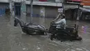 Seorang pria membawa kuda menyeberangi jalan yang banjir setelah hujan deras di Lahore, Pakistan (16/7/2019). Di Kashmir yang dikelola Pakistan, para pejabat pemerintah mengatakan sedikitnya 23 orang tewas setelah hujan lebat memicu banjir bandang. (AP Photo/K.M. Chaudary)