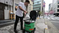 Seorang karyawan restoran menempatkan pesanan makanan di dalam robot tanpa awak selama uji coba layanan pengiriman robot oleh Uber Eats Japan, Mitsubishi Electric dan pengembang robot Cartken di pusat kota Tokyo pada tanggal 5 Maret 2024. (Richard A. Brooks/AFP)
