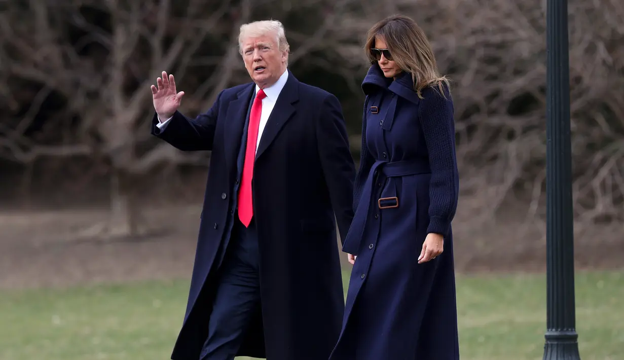 Presiden AS Donald Trump dan Melania Trump berjalan keluar dari Oval Office, Gedung Putih menuju helikopter kepresidenan, Senin (19/3). Melania terlihat modis memakai boots coklat Gianvito Rossi seharga sekitar Rp 22 juta. (AP/Pablo Martinez Monsivais)