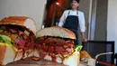 Chef dari restoran The Oak Door, Patrick Shimada berpose dengan burger raksasa di hotel Grand Hyatt Tokyo, Senin (1/4). Restoran itu membuat hamburger wagyu seukuran bola sepak yang disajikan dengan roti bertabur emas untuk merayakan penobatan kaisar baru Jepang bulan depan. (CHARLY TRIBALLEAU/AFP)