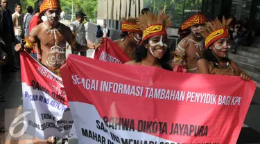 Sejumlah pemuda Papua mengenakan pakaian adat membawa spanduk berunjuk rasa di depan Gedung KPK, Jakarta, Senin (19/12). Mereka meminta KPK mengusut kasus korupsi pejabat yang mencalonkan diri pada Pilkada Jayapura 2017. (Liputan6.com/Helmi Affandi)