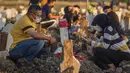 Keluarga berdoa untuk kerabat mereka di lokasi pemakaman korban virus corona COVID-19 di TPU Keputih, Surabaya, Jawa Timur, Sabtu (17/7/2021). Di Kota Surabaya terdapat dua tempat lahan pemakaman khusus blok COVID-19 yakni TPU Keputih dan TPU Babat Jerawat. (JUNI KRISWANTO/AFP)