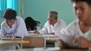 Seorang pria tampak sedang mengerjakan soal Ujian Nasional (UN) kesetaraan paket B di SMPN 80 Jakarta, Senin (4/5/2015). Sebanyak 378 peserta, termasuk peserta berusia lanjut mengikuti UN di hari pertama tersebut. (Liputan6.com/Johan Tallo)