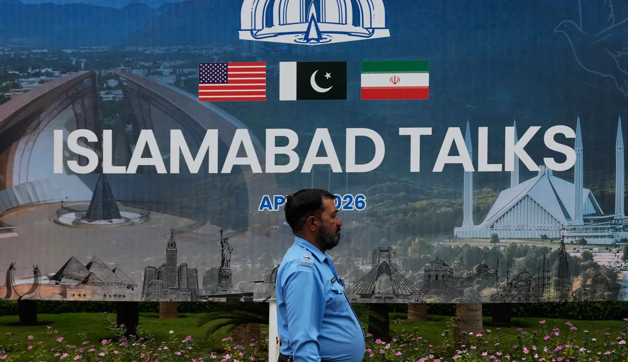 Diketahui, Amerika Serikat dan Iran saat ini berada dalam masa gencatan senjata selama dua minggu yang mulai berlaku sejak Rabu, 8 April 2026. Tampak dalam foto, seorang petugas polisi berjalan melewati papan reklame mengenai negosiasi Amerika Serikat dan Iran, di luar pusat fasilitasi media di Islamabad, Pakistan, Sabtu, 11 April 2026. (AP Photo/Anjum Naveed)