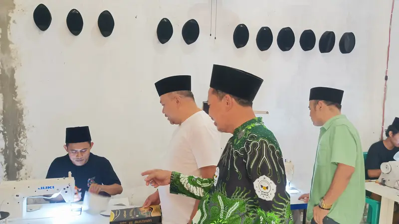 Pengasuh Ponpes Bumi Damai Al Mustawa, KH Muzayin ketika memperlihatkan kepada Anggota DPRD Jawa Tengah, H Abdullah Aminudin saat santri alumni pesantren setempat memproses pembuatan peci hitam. (Liputan6.com/Ahmad Adirin)