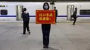 Petugas memegang papan bertuliskan ‘Stasiun Hankou menyambut Anda!’ saat para penumpang menaiki kereta pertama yang beroperasi usai berakhirnya lockdown akibat pandemi virus corona COVID-19 di Stasiun Hankou, Wuhan, Provinsi Hubei, China, Rabu (8/4/2020). (AP Photo/Ng Han Guan)