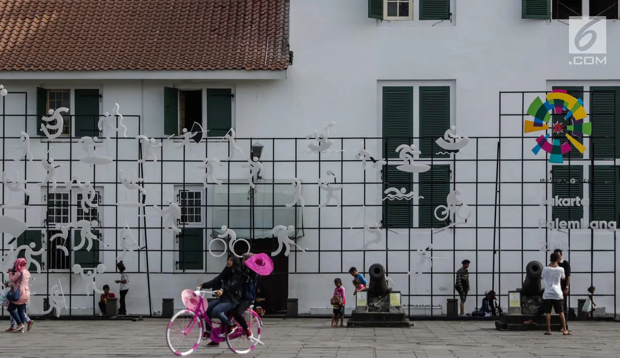Sejumlah pengunjung berdiri dekat ornamen Asian Games 2018 yang menghiasi kawasan Kota Tua, Jakarta, Senin (4/12). Adapun perhelatan akbar olahraga Asian Games 2018 akan digelar mulai 18 Agustus di Jakarta dan Palembang. (Liputan6.com/Faizal Fanani)