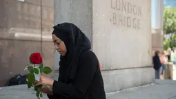 Seorang muslim bersiap membagikan bunga mawar kepada pejalan kaki di London Bridge, Minggu (11/6). Ribuan bunga mawar yang dibagikan sebagai solidaritas atas serangan teror London itu merupakan hasil donasi para warga Muslim. (David Mirzoeff/PA via AP)