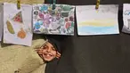 Seorang anak melihat melalui lubang di selimut selama pameran yang menampilkan koleksi gambar oleh anak-anak dan perempuan di sebuah sekolah yang diubah menjadi tempat penampungan bagi pengungsi Palestina di kawasan Al-Rimal, Kota Gaza, pada 5 November 2025. (Omar AL-QATTAA/AFP)