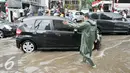 Petugas mengatur lalu lintas kendaraan yang melintas di Jalan Teuku Cik Ditiro, Jakarta, Selasa (30/8). Jalan Teuku Cik Ditiro tergenang air akibat hujan deras yang mengguyur Jakarta siang tadi. (Liputan6.com/Yoppy Renato)