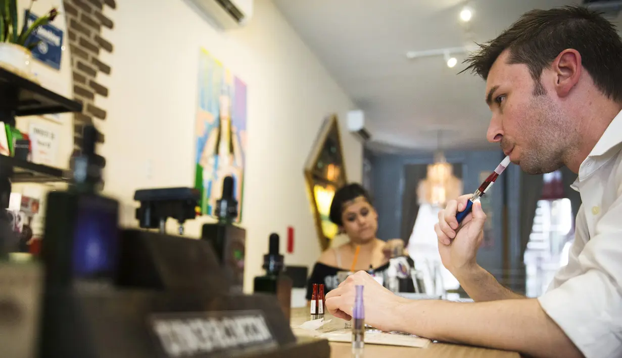 Pembeli mencoba rokok elektrik atau vape di sebuah toko rokok elektrik bernama Henley Vaporium, New York, AS 23 Juni 2015. Jelang peraturan tentang pengetatan penjualan vape di Amerika, Produsen Vape malah kebanjiran orderan.  (REUTERS / Lucas Jackson)