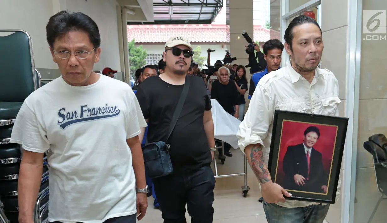 Anak Benny Panjaitan, Dino membawa foto sang ayah saat disemayamkan di rumah duka RS Dharmais, Jakarta, Selasa (24/10). Benny akan dimakamkan di TPU Menteng Pulo beberapa hari ke depan usai prosesi pemakaman adat Batak. (Liputan6.com/Herman Zakharia)