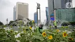 Petugas Dinas Pertamanan dan Hutan DKI Jakarta menata bunga matahari pada plater box di Bundaran HI, Jakarta, Jumat (18/6/2021). Pemasangan bunga matahari di kawasan Bundaran HI dalam rangka menyambut HUT ke-494 DKI Jakarta sekaligus mempercantik kawasan tersebut. (Liputan6.com/Faizal Fanani)
