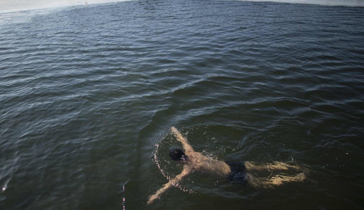 Seorang pria saat berenang di danau Hou Hai yang membbeku di Beijing, China (24/1). (AFP Photo/Nicolas Asfouri)