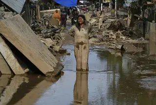 Kementerian Kesehatan sudah mengeluarkan peringatan adanya potensi lonjakan dua penyakit pasca bencana banjir bandang dan tanah longsor di Aceh, yaitu Demam Berdarah Dengue (DBD) dan Leptospirosis. Tampak dalam foto, seorang perempuan berlumuran lumpur berdiri di jalanan yang dipenuhi lumpur setelah banjir bandang melanda daerah tersebut di Aceh Tamiang, Provinsi Aceh, pada Sabtu 6 Desember 2025. (YT HARIONO/AFP)