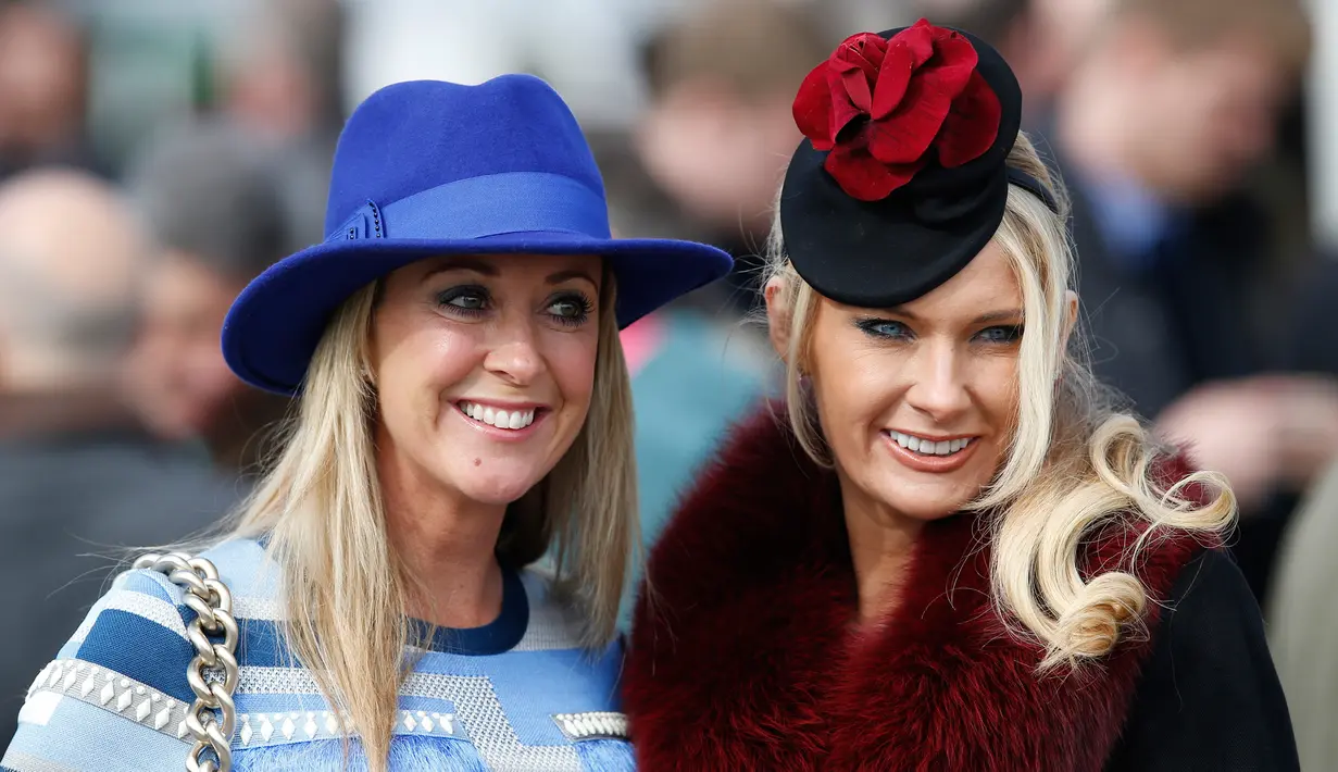 Senyum manis dua wanita cantik saat difoto jelang pembukaan ajang Pacuan Kuda dalam Festival Cheltenham di Inggris (16/3). Para wanita yang menghadiri pacuan kuda ini terkenal dengan gaya modisnya dan topi fancy yang dikenakannya. (REUTERS/Paul Childs)