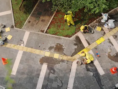 Pasukan Kuning dari Dinas Bina Marga memperbaiki garis kuning di trotoar kawasan Tanah Abang, Jakarta, Sabtu (22/5/2021). Garis kuning di trotoar yang dibuat khusus untuk jalur penyandang tunanetra tersebut diperbaiki agar nantinya dapat dilintasi dengan aman dan nyaman. (Liputan6.com/Angga Yuniar)