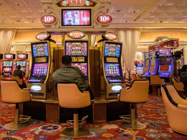 Pengunjung bermain mesin slot di sebuah resor di Macau, 5 Maret 2019. Macau merupakan kota judi terbesar di Asia. (Anthony Wallace/AFP)