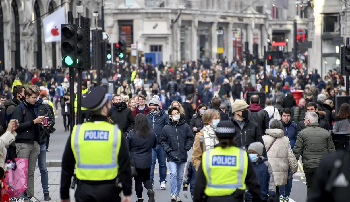 Orang-orang berjalan dengan mengenakan masker dan membawa tas belanjaan di Regent Street, setelah pelonggaran pembatasan virus corona COVID-19 menyusul berakhirnya kebijakan penguncian nasional atau lockdown kedua di Inggris, di London, Sabtu (5/12/2020). (AP Photo/Alberto Pezzali)