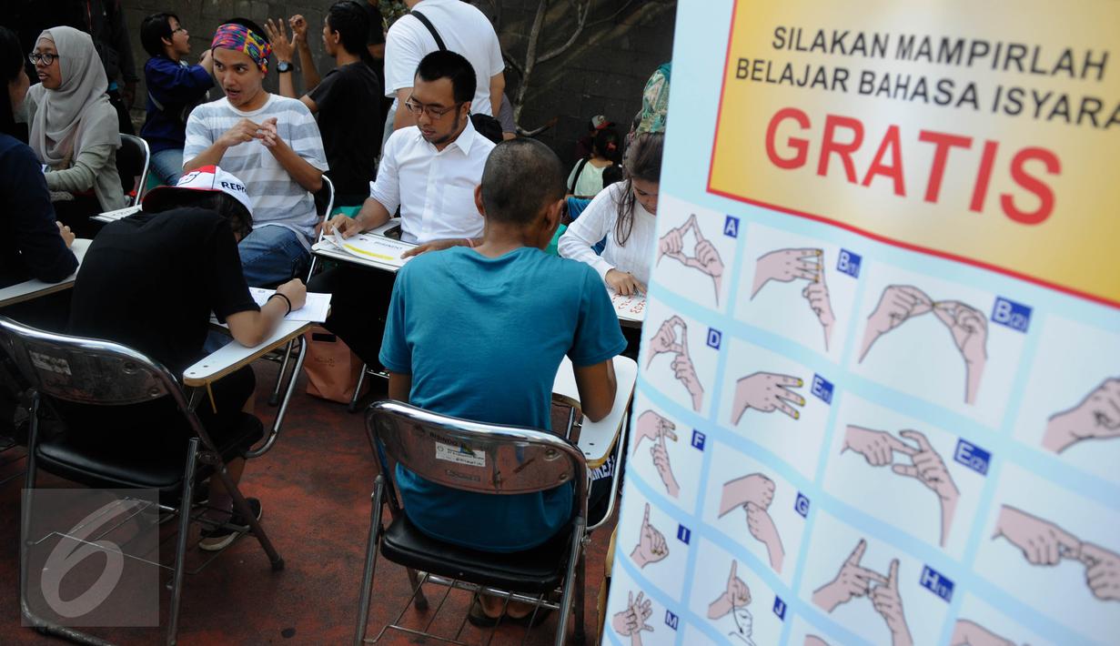 Pelatih mengajarkan bahasa isyarat saat aksi sosialisasi di Car Free Day (CFD), Jakarta, Minggu (11/9). Sosialisasi belajar bahasa isyarat untuk mengkampanyekan penggunaan bahasa isyarat dalam dialog para penyandang tuna rungu (Liputan6.com/Faizal Fanani)