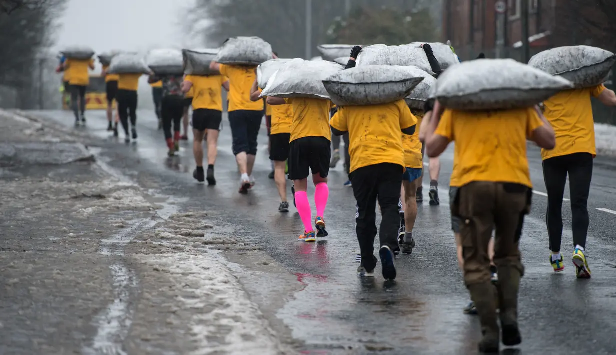 Peserta membawa karung berisi batu bara saat mengikuti World Coal Carrying Championships di Desa Gawthorpe, Wakefield, Inggris Utara, Senin (2/4). Kompetisi  tahunan mengakut karung batu bara ini diikuti oleh pria, wanita dan anak-anak. (OLI SCARFF/AFP)
