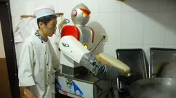 Seorang koki melihat robot yang sedang membuat mie di sebuah restoran,  Beijing , Cina , 14 April 2016. Kita akan melihat berbagai kebiasaan unik warga Cina. (REUTERS / Stringer)