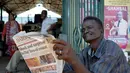 Seorang pria membaca koran sambil menunggu hasil resmi pemilihan umum Kenya di luar pasar sentral di Mombasa (10/8). Warga Kenya tengah menunggu hasil pemilihan presidennya, antara Uhuru Kenyatta dan pesaingnya, Raila Odinga. (AFP Photo/Tobin Jones)