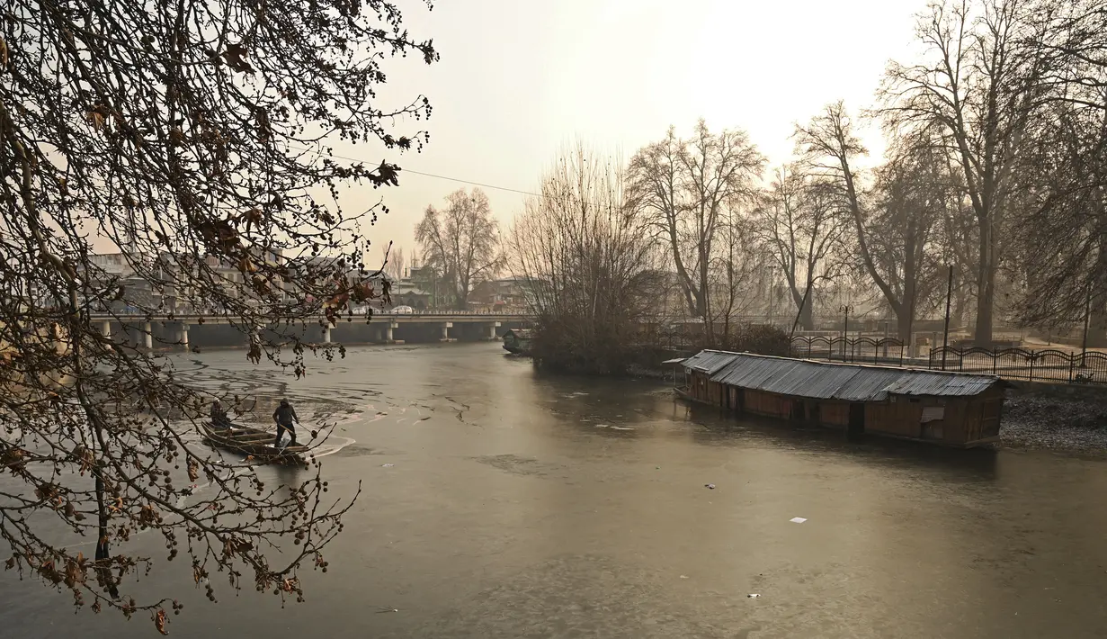 Tukang perahu menggunakan dayung memecahkan lapisan es di sepanjang bagian dalam Danau Dal pada pagi saat musim dingin di Srinagar (2/1/2023). Periode musim dingin yang keras selama 40 hari yang dikenal sebagai 'Chillai Kalan' memperketat cengkeramannya di Kashmir pada hari Senin karena suhu malam semakin turun. (AFP/Tauseef Mustafa)