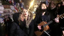 Penyanyi Madonna dan putranya David Banda diiringi gitaris Monte Pittman menggelar konser jalanan di Place de la Republique, dekat tempat peringatan para korban serangan 13 November Paris yang menewaskan 130 orang, Kamis (10/12/2015). (JULES MAHE/AFP)