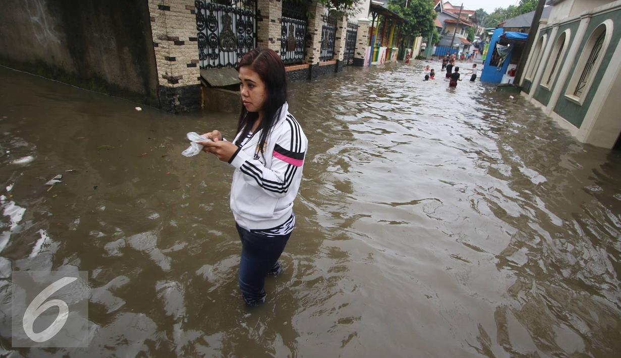 Warga melintasi banjir yang menggenangi Jalan Ketapang di kawasan Pasar Minggu, Jakarta, Selasa (4/10). Banjir yang berasal dari luapan Kali Anur tersebut menyebabkan Jalan Ketapang tidak bisa dilewati kendaraan. (Liputan6.com/Immanuel Antonius)