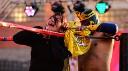 Pegulat Bolivia, Blanca Perez dikunci oleh lawannya pegulat pria di atas ring gulat di El Alto, pada 24 November 2019. Di Bolivia ada sebuah atraksi gulat yang diperankan perempuan dengan menggunakan busana khas warga Bolivia. (Ronaldo SCHEMIDT / AFP)