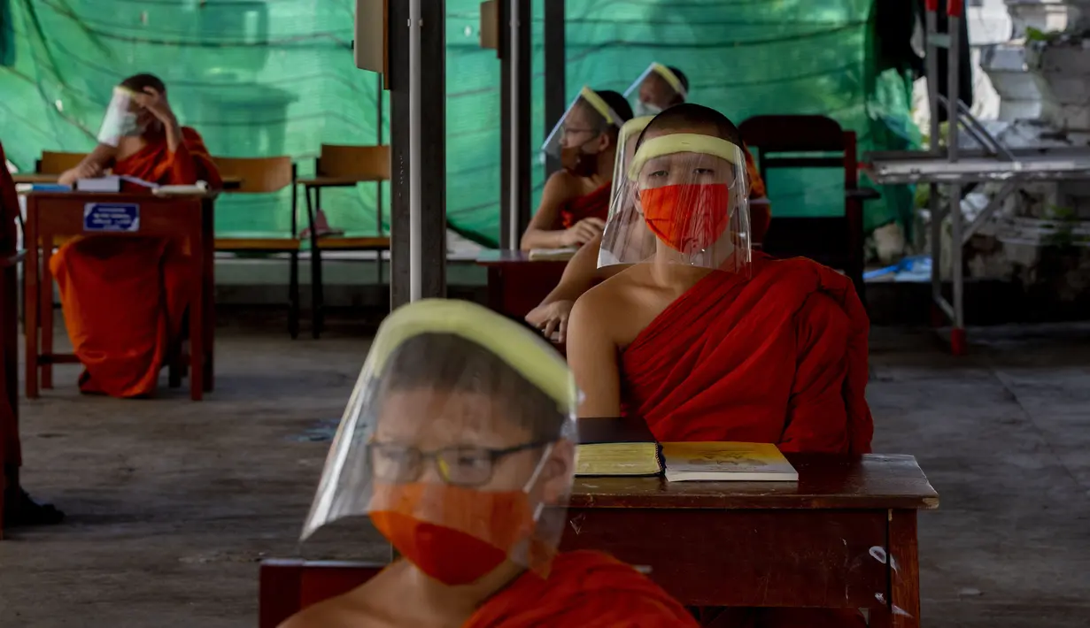 Para biksu muda mengenakan masker dan pelindung wajah saat belajar agama di Molilokayaram Educational Institute, Bangkok, Thailand, Rabu (15/4/2020). Sekitar 200 biksu muda tetap bersekolah kendati Thailand menutup semua sekolah selama lockdown akibat COVID-19. (AP Photo/Gemunu Amarasinghe)