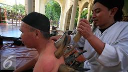 Terapis menempelkan tanduk ke punggung pasiennya di Masjid Malioboro, Yogyakarta, Minggu (17/4). Bekam yang menggunakan tanduk tersebut merupakan pengobatan alternatif yang berkhasiat untuk mengobati berbagai macam penyakit. (Liputan6.com/Boy Harjanto)