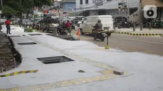 Kendaraan melintas di samping proyek revitalisasi trotoar di kawasan Senopati, Kebayoran Baru, Jakarta, Rabu (15/9/2021). Pemprov DKI Jakarta melalui Dinas Bina Marga merevitalisasi 10 ruas jalan di lima wilayah kota adminsitrasi Jakarta sampai akhir tahun 2021. (Liputan6.com/Herman Zakharia)