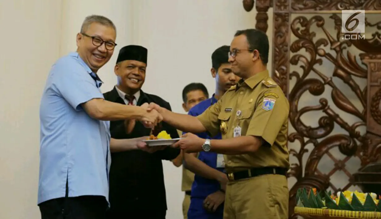 Gubernur DKI Jakarta Anies Baswedan (kanan) menyerahkan nasi tumpeng kepada Dirut PT Transjakarta Budi Kaliwono, Jakarta, Selasa (20/3). Menurut Anies, Transjakarta harus bisa menjadi model pengelolaan transportasi massal. (Liputan6.com/Pool/Dadang WS)