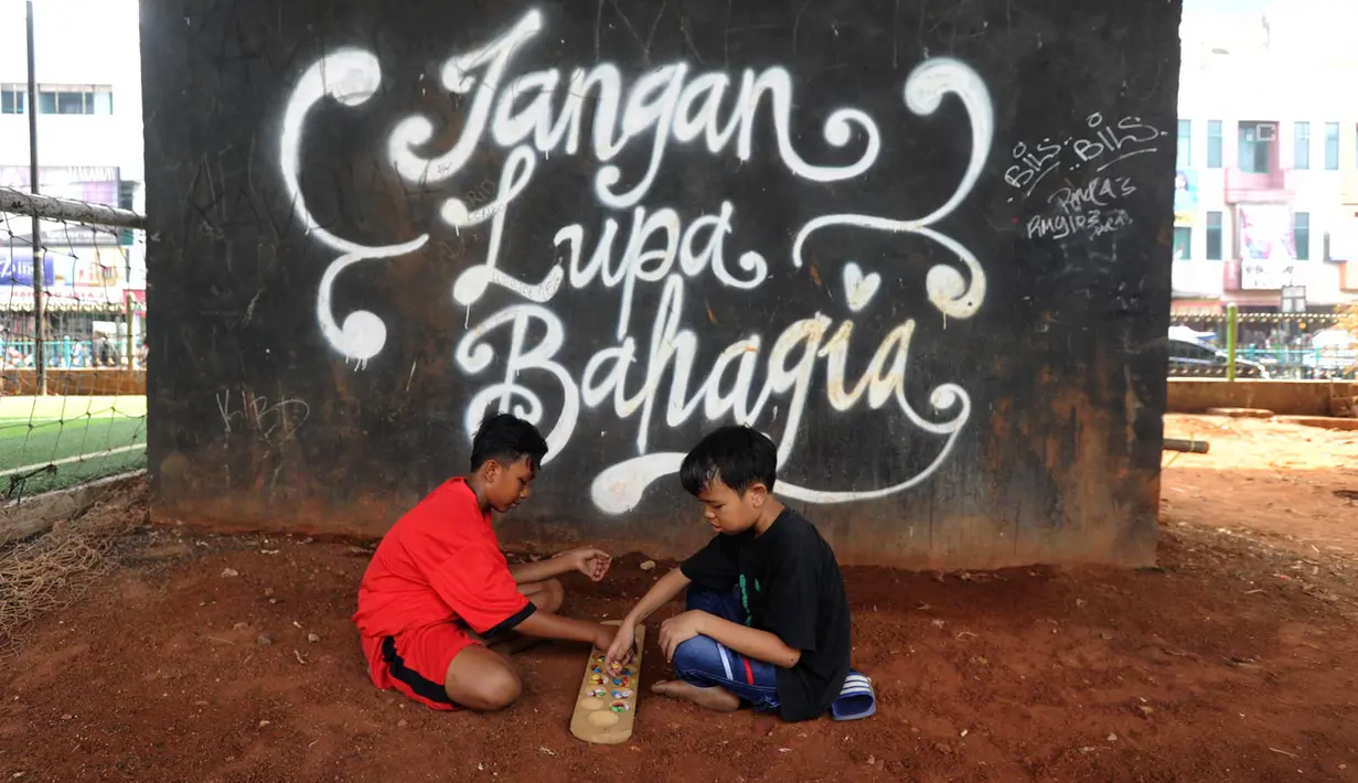 Anak-anak bermain congklak di Taman Bermain Masyarakat (TBM) Kolong Ciputat, Tangsel, Banten, Minggu (22/7). (Merdeka.com/Arie Basuki)