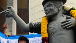 Seorang pria mengambil foto bersama patung bintang pop AS Michael Jackson di Chennai, India, Kamis (7/4). Patung ini dibangun disebuah Universitas ternama di India. (Arun Sankar/AFP)