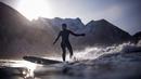 Peselancar wanita beraksi menantang hawa dingin di Lofoten Islands, Norwegia, (10/3/2018). Suhu udara minus 13°C dan suhu diatas air sekitar 4°C. (AFP/Oliver Morin)