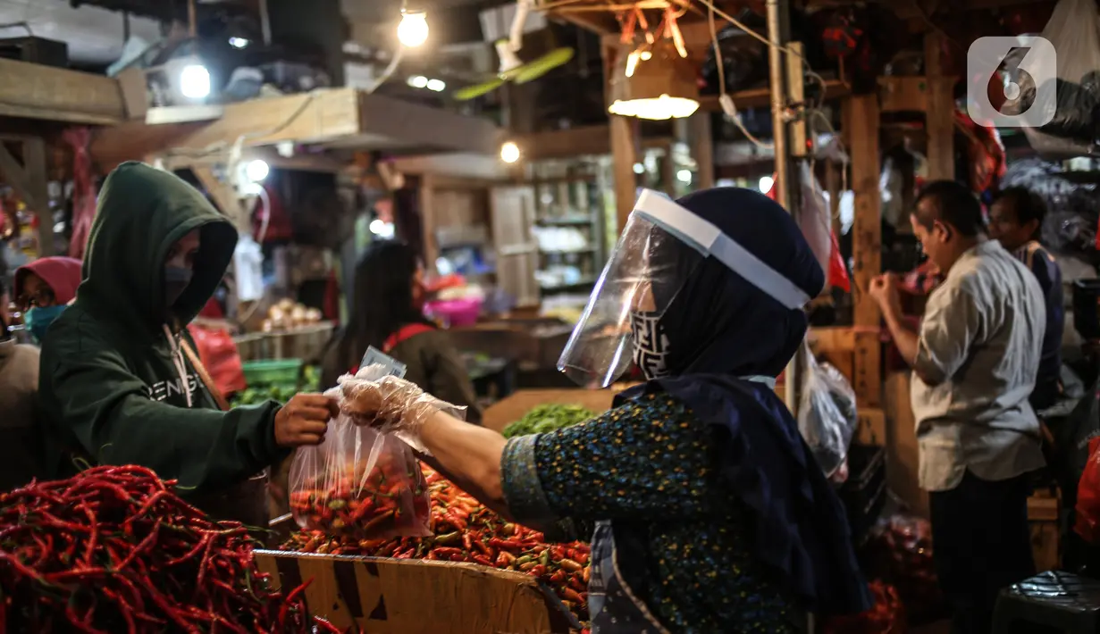 Salah satu pedagang menggunakan face shield dan sarung tangan saat melayani pembeli di Pasar Senen, Jakarta, Senin (1/6/2020). Saat era new normal, para pedagang di pasar rakyat diwajibkan menggunakan masker, face shield, dan sarung tangan selama beraktivitas. (Liputan6.com/Faizal Fanani)