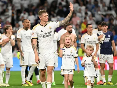 Pemain Real Madrid, Toni Kroos (tengah) bersama anak-anaknya saat melakukan perpisahan setelah laga Liga Spanyol 2023/2024 melawan Real Betis di Santiago Bernabeu, Madrid, Spanyol, Minggu (26/05/2024) dini hari WIB. Kroos memutuskan untuk pensiun dari sepak bola setelah Euro 2024 nanti. (AFP/Javier Soriano)