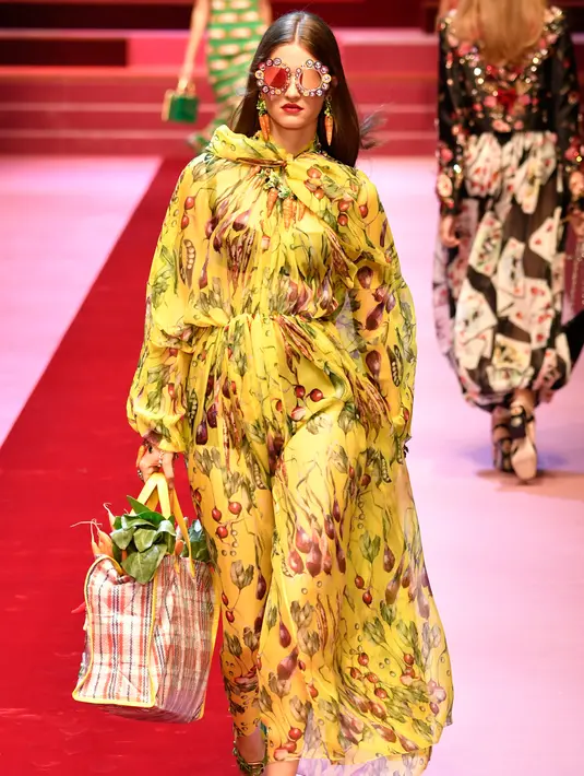 Seorang model berjalan membawa tas besar mirip tas pasar berisi sayuran untuk koleksi Dolce & Gabbana Spring/Summer 2018 pada Milan Fashion Week, Minggu (24/9). Tas pasar itu memiliki motif plaid dengan pinggiran warna kuning. (AFP PHOTO / Andreas SOLARO)