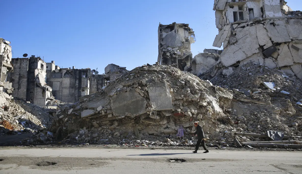Seorang pria berjalan melewati bangunan yang  hancur di Salaheddine, Aleppo, Suriah, 20 Januari 2018. Gejolak krisis ekonomi menyebabkan lonjakan harga makanan dan kebutuhan dasar di Suriah. (12/6/2020). (AP Photo/Hassan Ammar, File)
