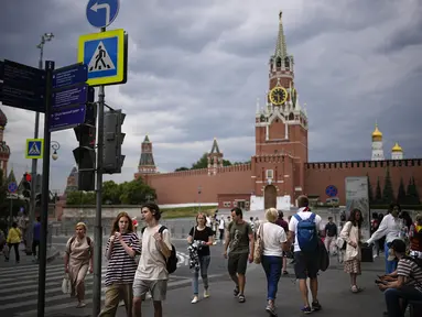 Orang-orang berjalan di depan Red Square yang ditutup dengan Tembok Kremlin dan Menara Spasskaya di latar belakang di Moskow, Rusia, Selasa, 27 Juni 2023. (AP Photo/Alexander Zemlianichenko)