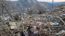 Seorang wanita mengambil dan mengumpulkan barang-barang pribadi yang masih bisa digunakan dari reruntuhan rumah mereka di desa Yaylakonak distrik Adiyaman, Turki, Minggu (19/2/2023). 108 jiwa meninggal dan 170 rumah ambruk di Desa Yaylakonak distrik Adiyaman, Turki akibat gempa berkekuatan 7,8 magnitudo yang terjadi pada 6 Februari lalu. (BULENT KILIC/AFP)